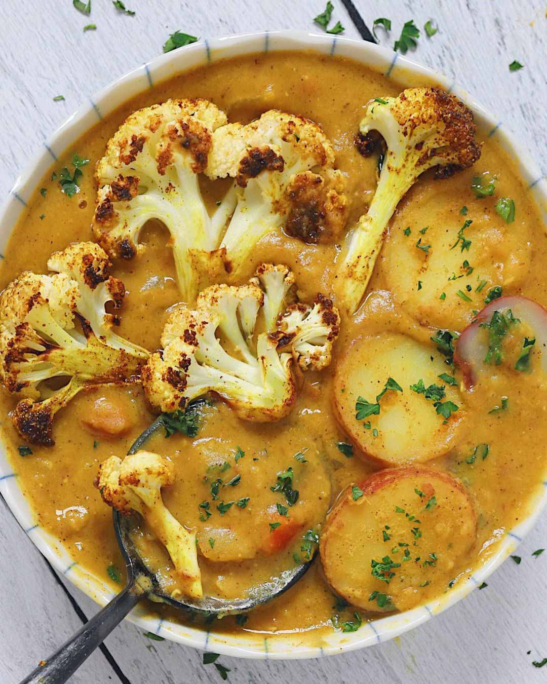 Roasted Cauliflower & Lentil Curry Soup recipe served in a bowl with spoon.