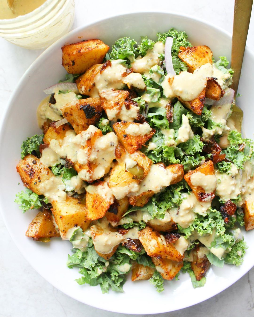 Spicy Potato Kale Bowl with Mustard Tahini Dressing recipe served in a bowl with spoon.