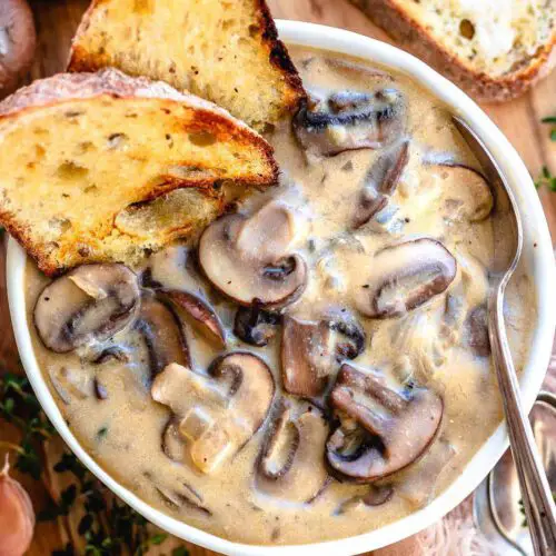 Vegan Cream of Mushroom Soup recipe displayed in a bowl with toasted bread and a spoon.