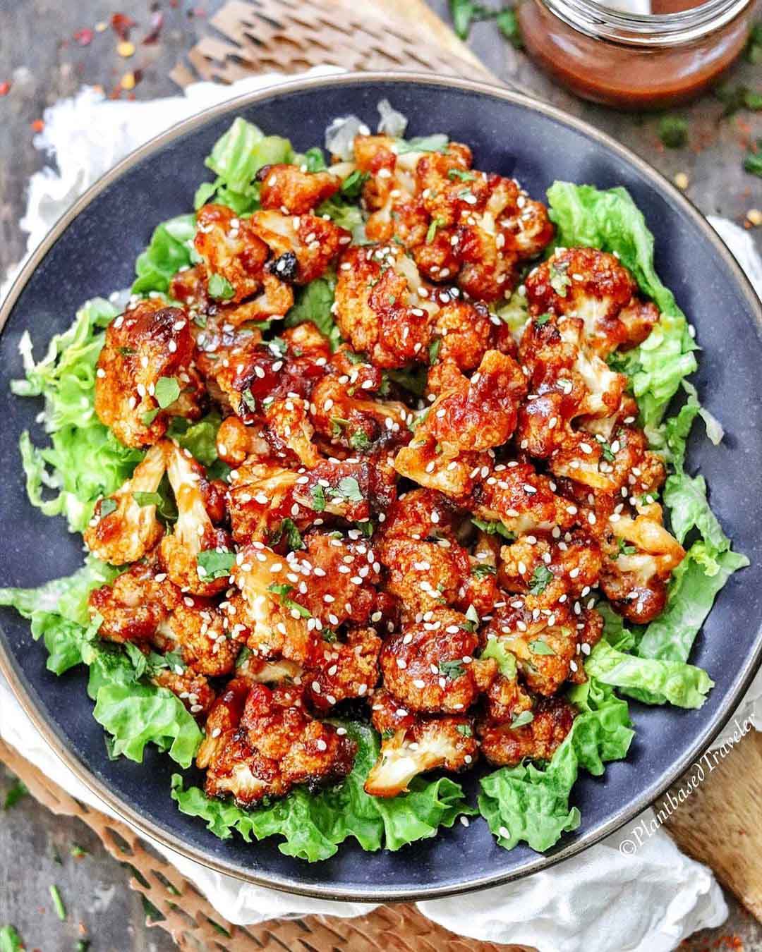 Roasted Bang Bang Cauliflower Bites recipe served in a bowl with lettuce.