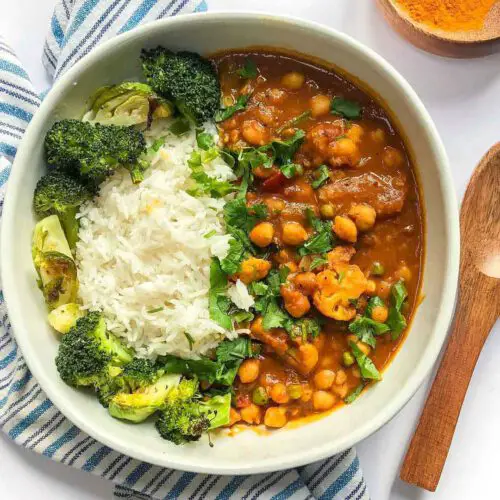 Coconut Curry Chickpeas with Cauliflower recipe served in a bowl with rice and broccoli.