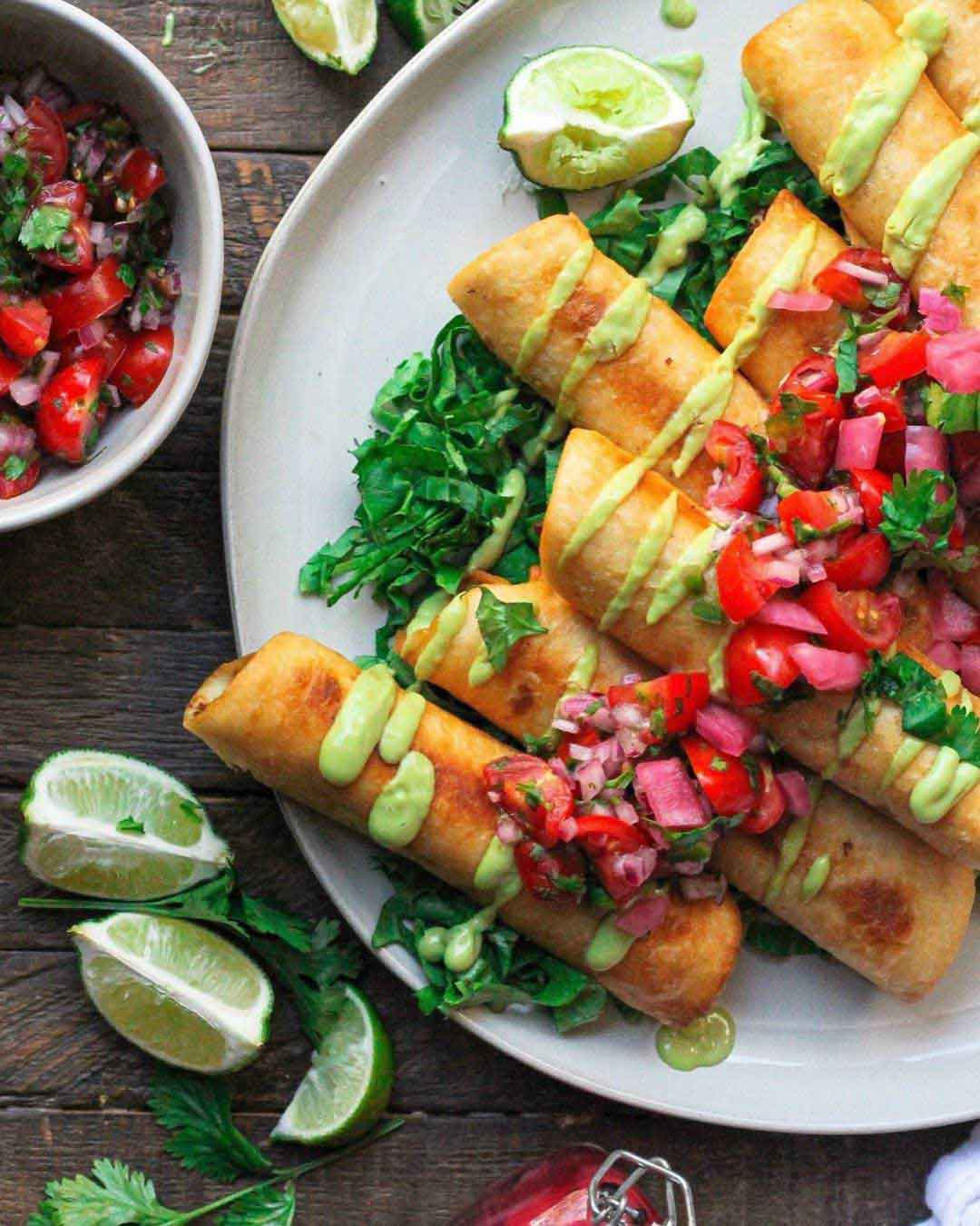 Vegan Chipotle Chick’n Flautas with Avocado Crema recipe served on a plate with fresh limes.